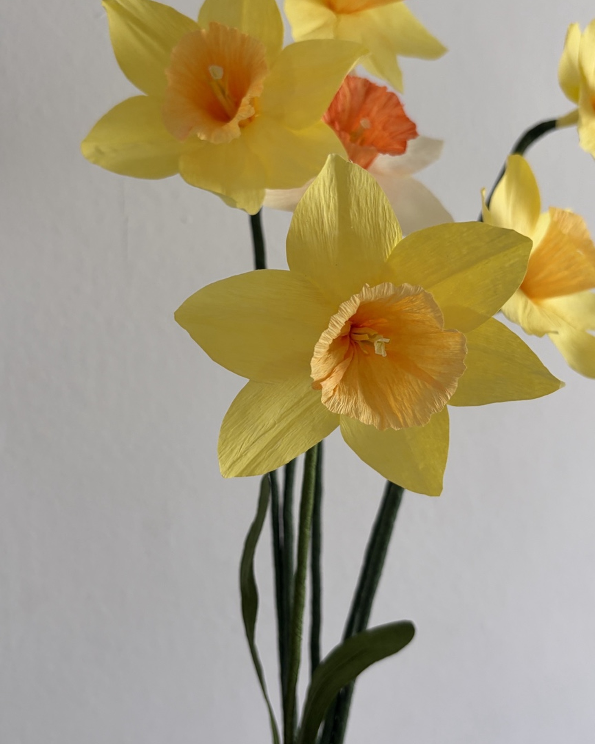 Detalle de narciso de papel amarillo con centro naranja hecho a mano