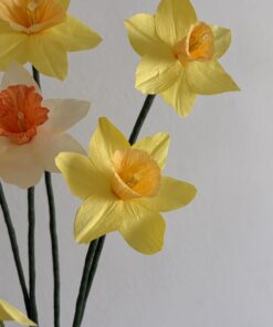 Primer plano de flores de papel tipo narciso con pétalos amarillos y centros naranjas