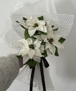 Ramo de tres Flores de Pascua blancas hechas a mano con papel crepé y hojas verdes, envuelto en papel de lunares.