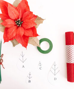 Flor de Pascua roja de papel junto a rollos de papel crepé, alambres, cinta floral y plantillas.